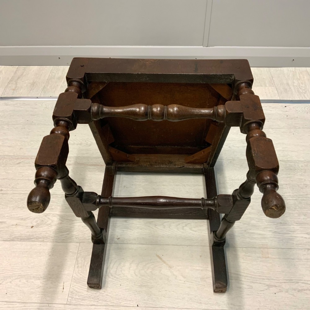 A late 17th-century dark oak back stool side chair featuring a solid wooden seat, central back splat, and turned front legs with stretchers. View VII