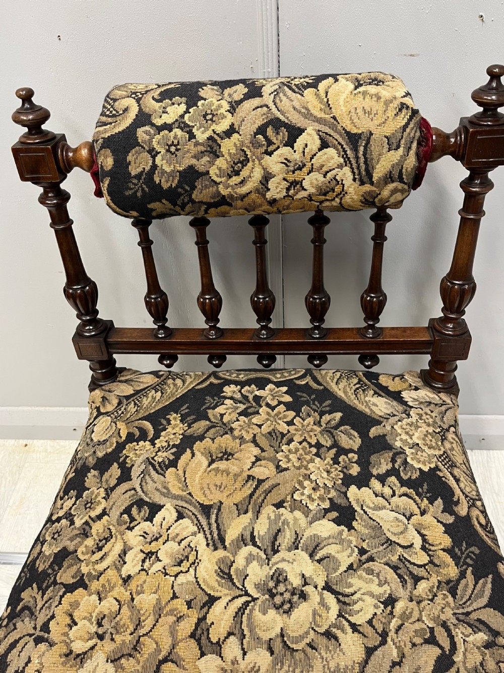 A Victorian low-seated prie-dieu prayer chair featuring turned wooden legs, a spindle back gallery, and black and gold floral tapestry fabric. View II