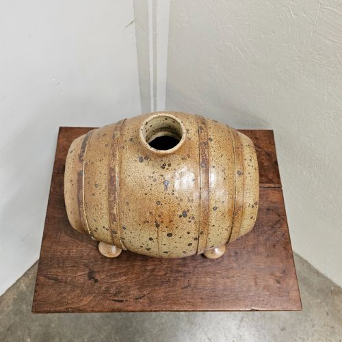 fig 2. A horizontal ceramic barrel-shaped stoneware vinegar vessel with a speckled salt glaze finish, raised top opening, simulated wooden hoops, and integrated stoneware feet.