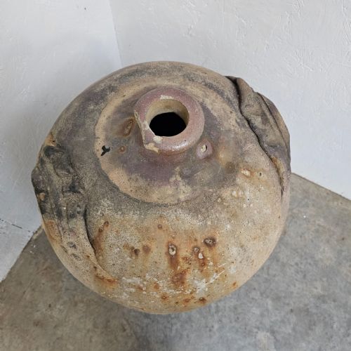 fig 1. A large French earthenware walnut oil jar featuring a narrow rimmed mouth, dual shoulder lugs, and a textured earthy brown patina.