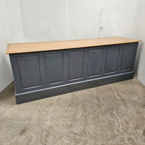 fig 1. A long French shop counter featuring twelve drawers painted in dark grey with metal cup handles and a natural scrubbed pine top surface.