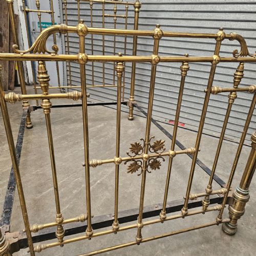 fig 2. An antique Victorian double bed frame crafted with vertical brass spindles, decorative brass rosettes, turned urn finials, and a black cast iron base.