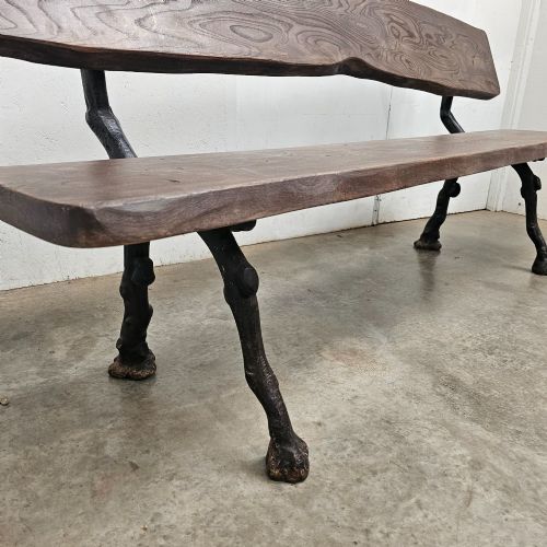 fig 1. A rustic French garden bench featuring a dark elm slab seat and backrest supported by black cast iron legs designed to resemble natural tree branches.