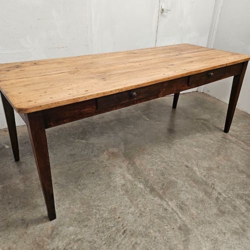 fig 2. An antique French farmhouse dining table with a light pine plank top, two apron drawers, and a dark oak frame with tapered legs.