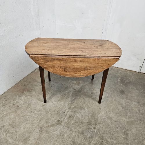 fig 1. An antique wooden French drop-leaf table with semi-circular side leaves folded down and four tapered wooden legs.