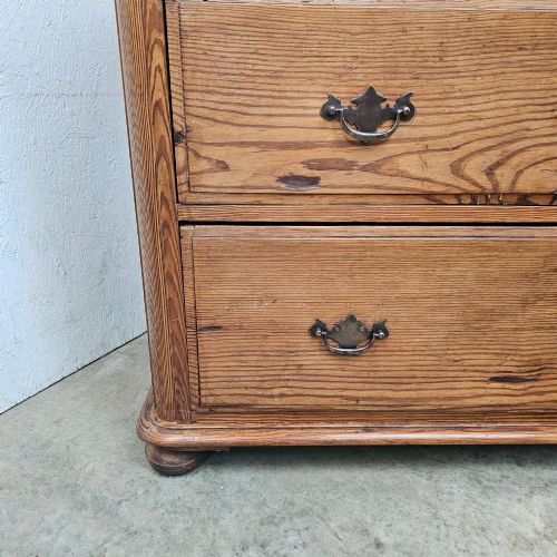 fig 2. A Victorian pitch pine chest of drawers featuring a two-over-two drawer layout with brass drop handles and a visible wood grain.