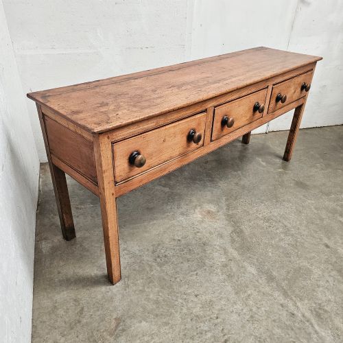 fig 2. An English country pine and elm dresser base featuring a planked top, three frieze drawers with turned knobs, and four square tapered legs.