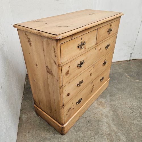 fig 1. A Victorian light pine chest of drawers featuring a two-over-three drawer configuration, brass drop handles, keyholes, and a solid plinth base.