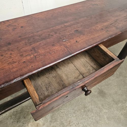 fig 3. An antique dark fruitwood console table featuring a single central drawer, straight legs, and an H-stretcher base.