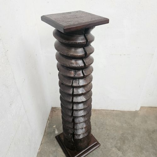 fig 1. A tall hand-carved dark timber wine press screw thread with a square top and base, repurposed as a sculptural display pedestal.
