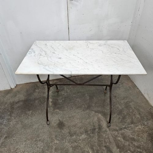 fig 1. A rectangular white veined marble top resting on a dark wrought iron base with curved legs and cross-bracing.