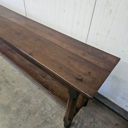 fig 1. A long, narrow dark oak French serving table featuring a plank top, square legs, and a full-length lower pot shelf.