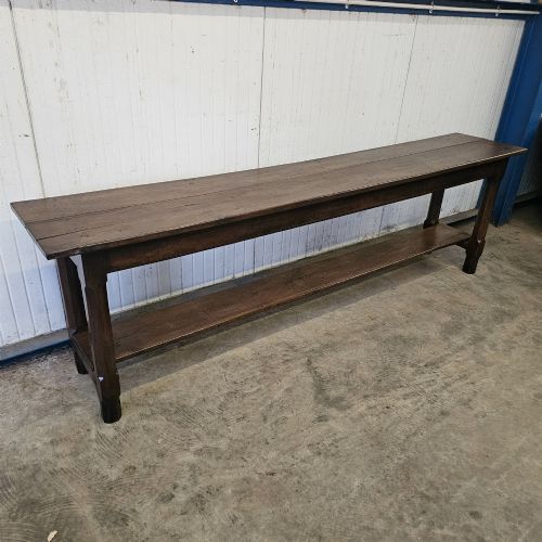 fig 3. A long, narrow dark oak French serving table featuring a plank top, square legs, and a full-length lower pot shelf.