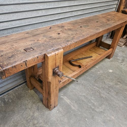 fig 1. A long, heavy French oak workbench with an integrated wooden vice, lower storage shelf, and aged iron hardware.
