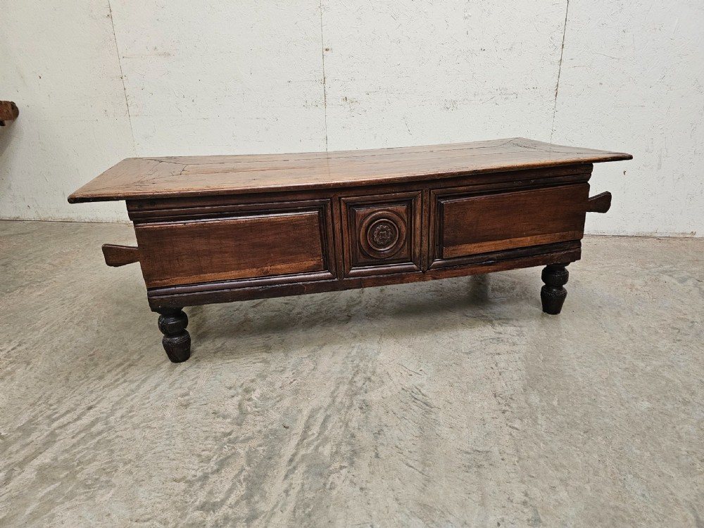 A low French fruitwood coffee table featuring three carved recessed front panels, side handles, and turned support feet.