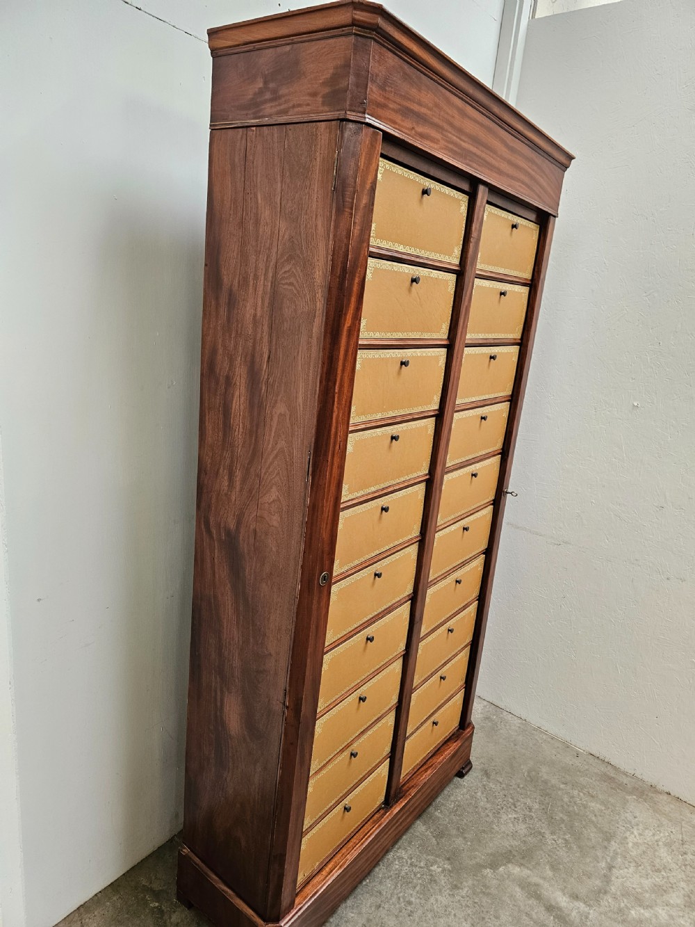 A tall French mahogany cartonnier cabinet with two vertical columns of drop-front drawers featuring gilt-tooled tan leather fronts. View III