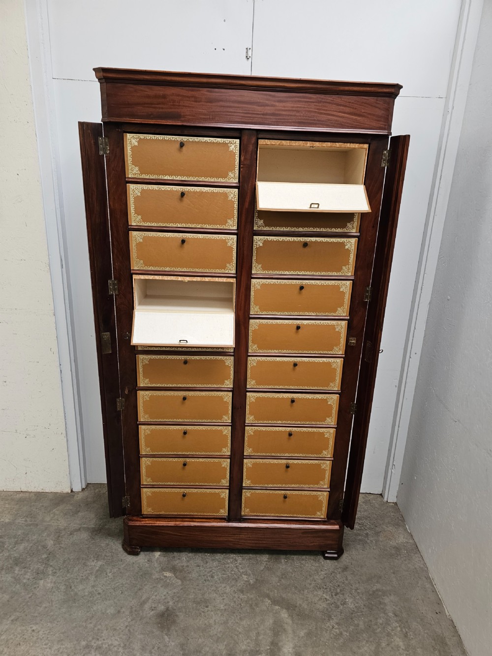A tall French mahogany cartonnier cabinet with two vertical columns of drop-front drawers featuring gilt-tooled tan leather fronts. View VI