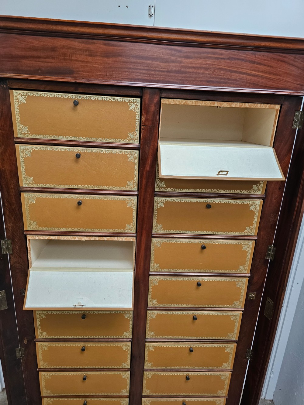 A tall French mahogany cartonnier cabinet with two vertical columns of drop-front drawers featuring gilt-tooled tan leather fronts. View VII