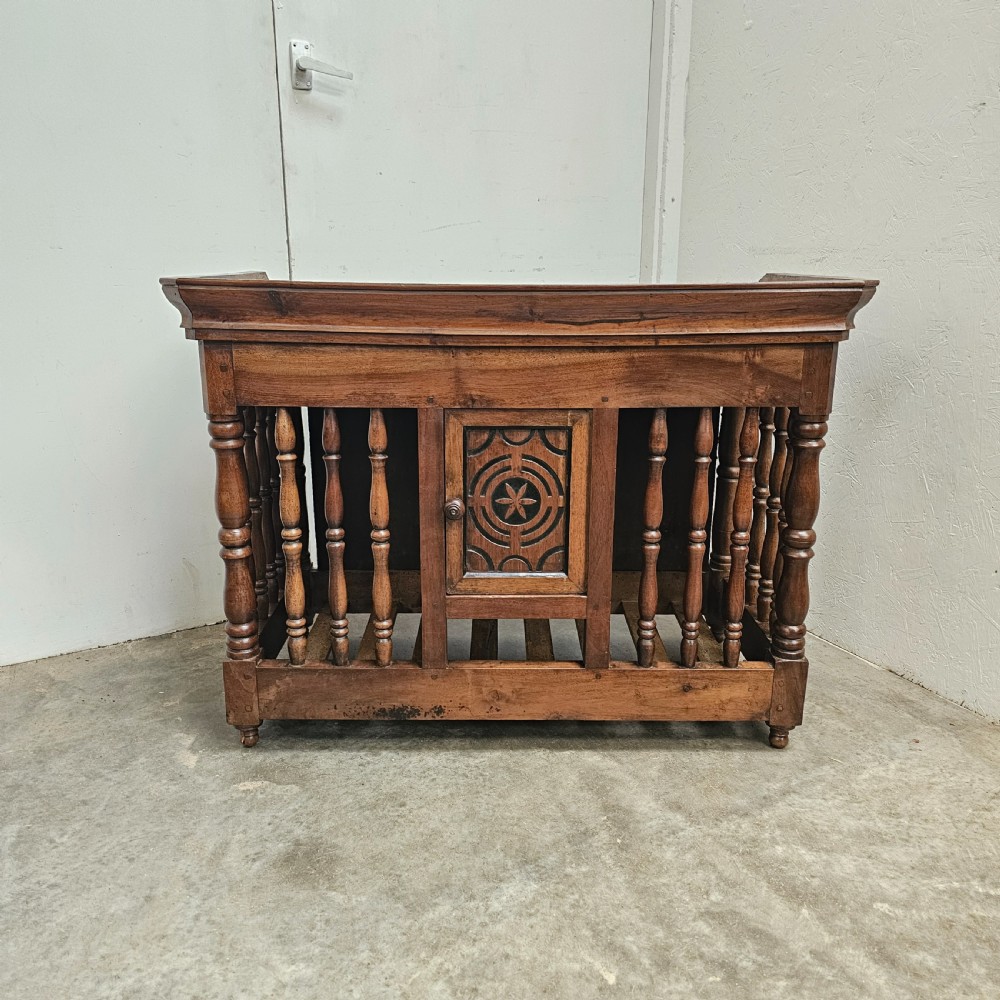 A 19th-century French provincial carved walnut panetiere featuring turned spindle balusters, a slatted base, and a central cupboard door carved with a geometric star motif.