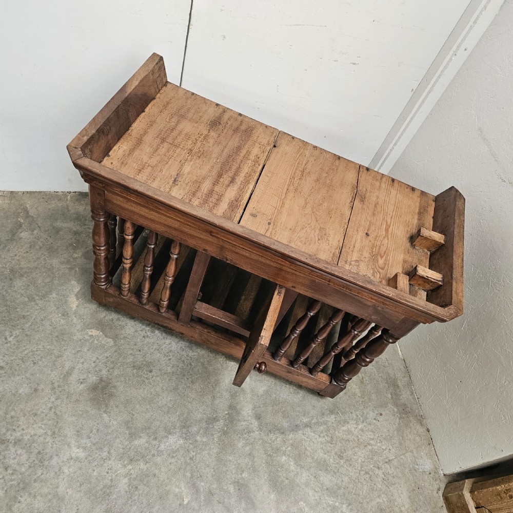 A 19th-century French provincial carved walnut panetiere featuring turned spindle balusters, a slatted base, and a central cupboard door carved with a geometric star motif. View III