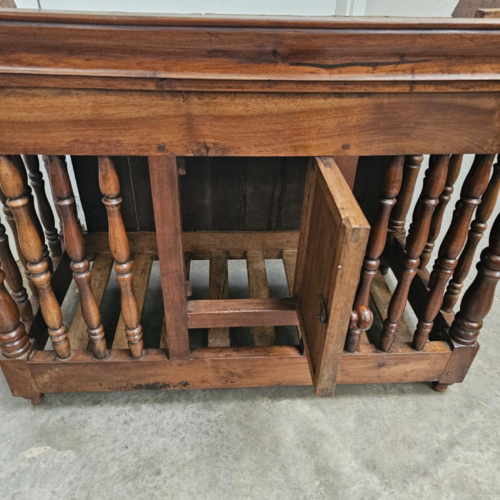 A 19th-century French provincial carved walnut panetiere featuring turned spindle balusters, a slatted base, and a central cupboard door carved with a geometric star motif. View V