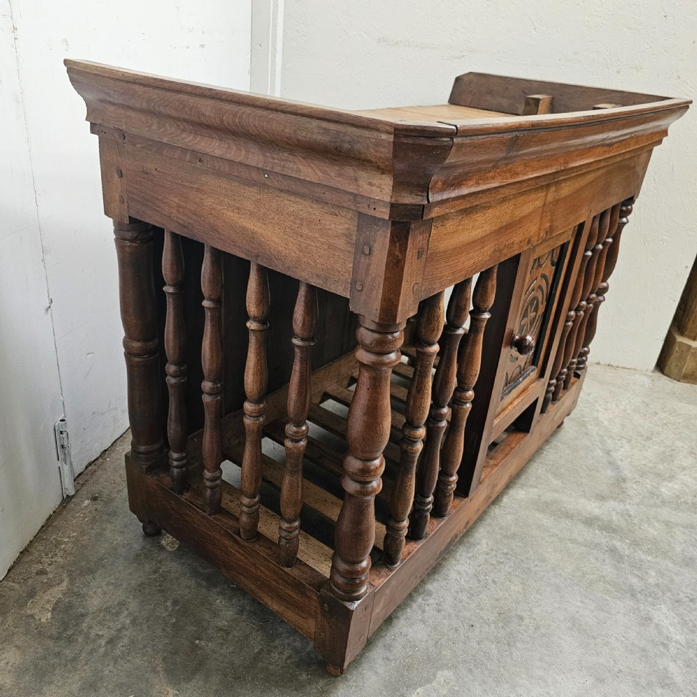 A 19th-century French provincial carved walnut panetiere featuring turned spindle balusters, a slatted base, and a central cupboard door carved with a geometric star motif. View VI