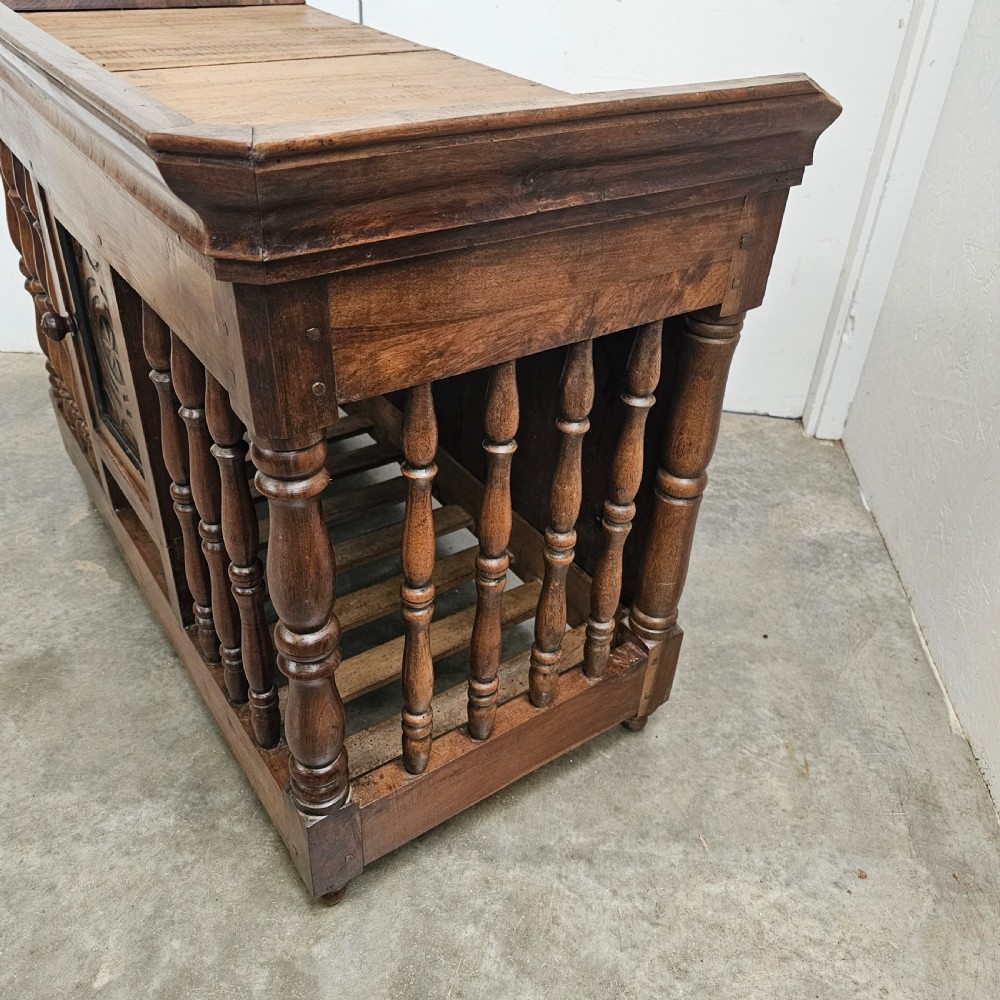 A 19th-century French provincial carved walnut panetiere featuring turned spindle balusters, a slatted base, and a central cupboard door carved with a geometric star motif. View VII