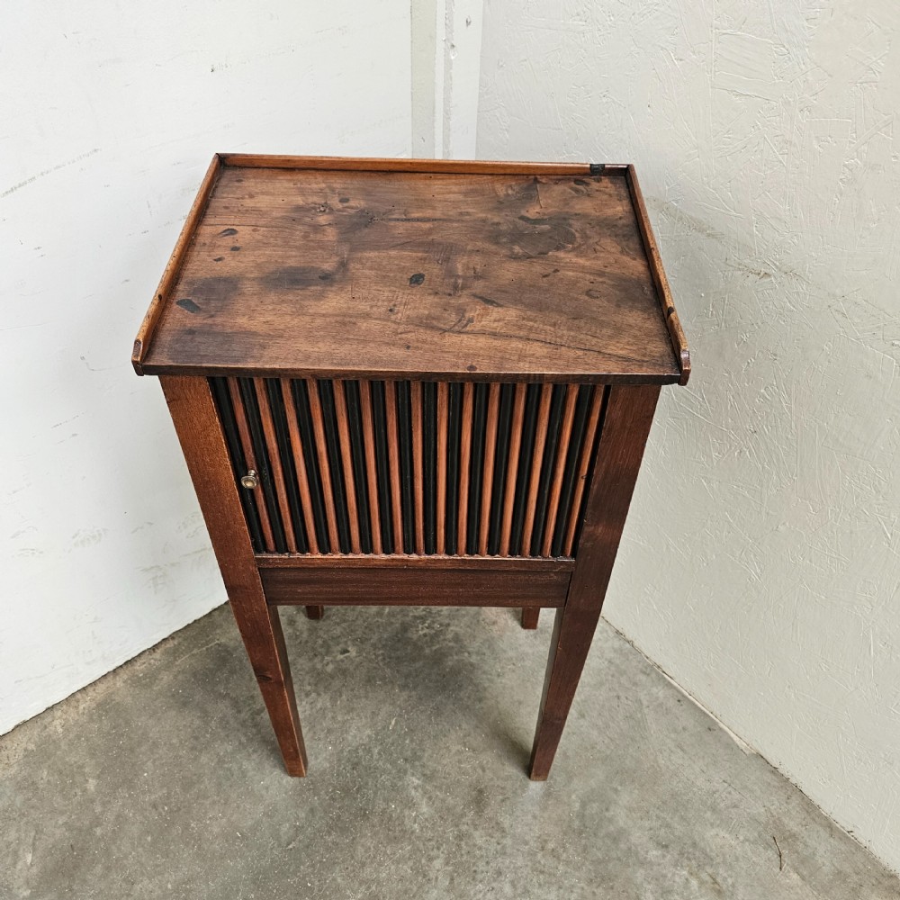A tall walnut bedside cabinet featuring a vertical tambour slatted door, square tapered legs, and a raised gallery top. View II