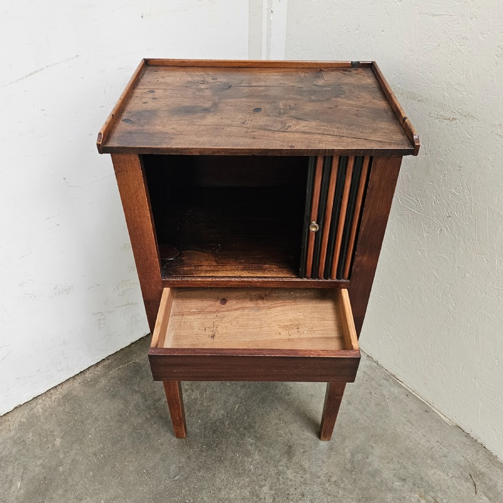 A tall walnut bedside cabinet featuring a vertical tambour slatted door, square tapered legs, and a raised gallery top. View V