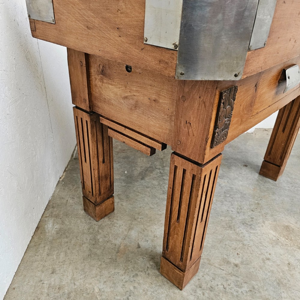 An antique French beech butchers block featuring a dished top surface, metal corner brackets, a single drawer, and carved square legs. View III
