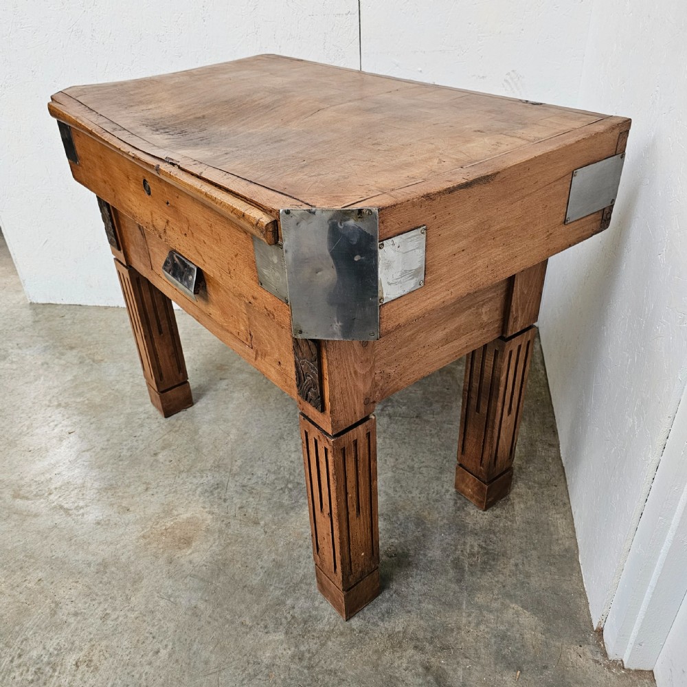 An antique French beech butchers block featuring a dished top surface, metal corner brackets, a single drawer, and carved square legs. View IV