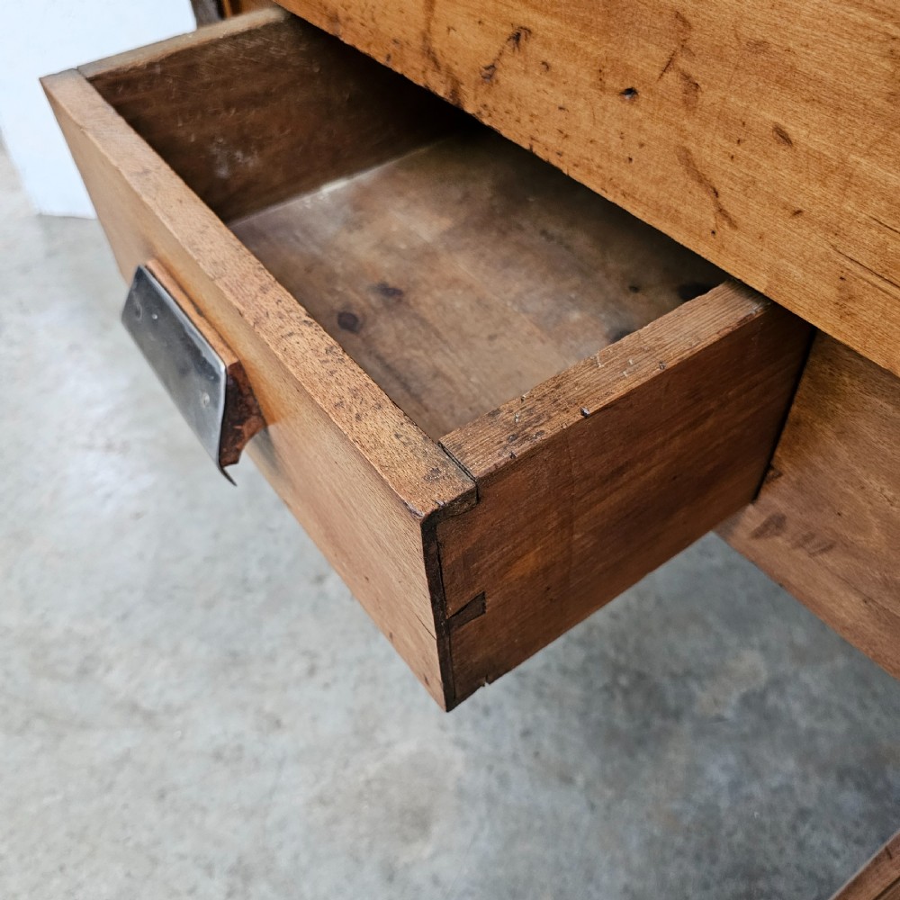 An antique French beech butchers block featuring a dished top surface, metal corner brackets, a single drawer, and carved square legs. View VI