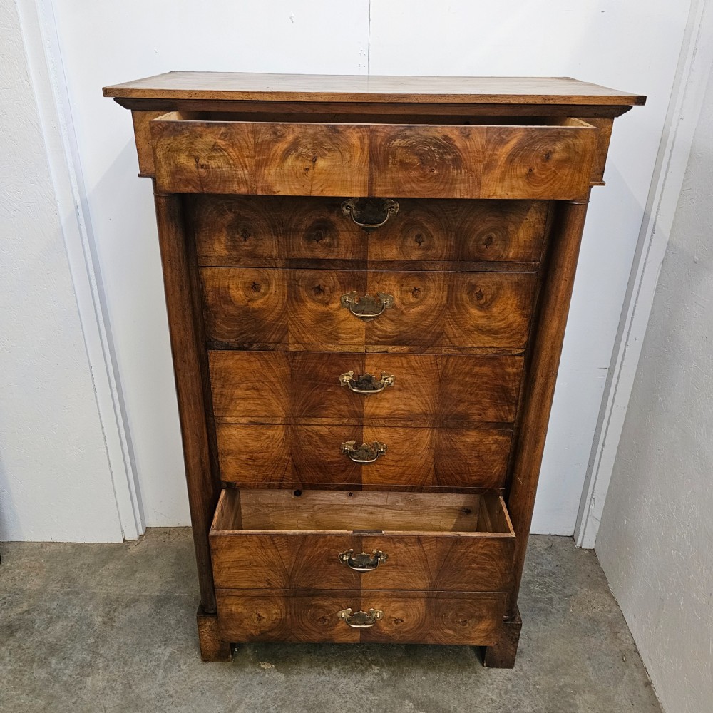 A tall 19th-century French Empire chest of drawers featuring bookmatched walnut grain veneer, flank column pilasters, and six stacked drawers with brass bail handles. View II