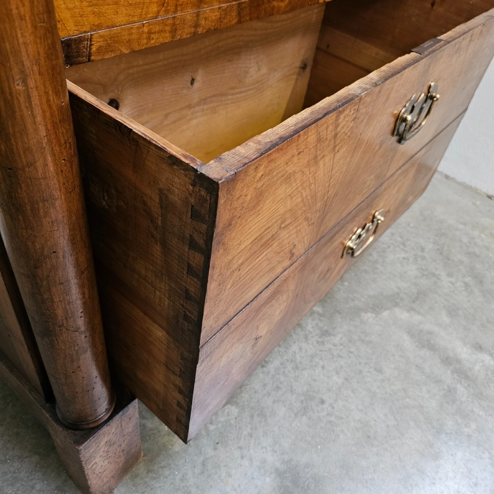 A tall 19th-century French Empire chest of drawers featuring bookmatched walnut grain veneer, flank column pilasters, and six stacked drawers with brass bail handles. View IV