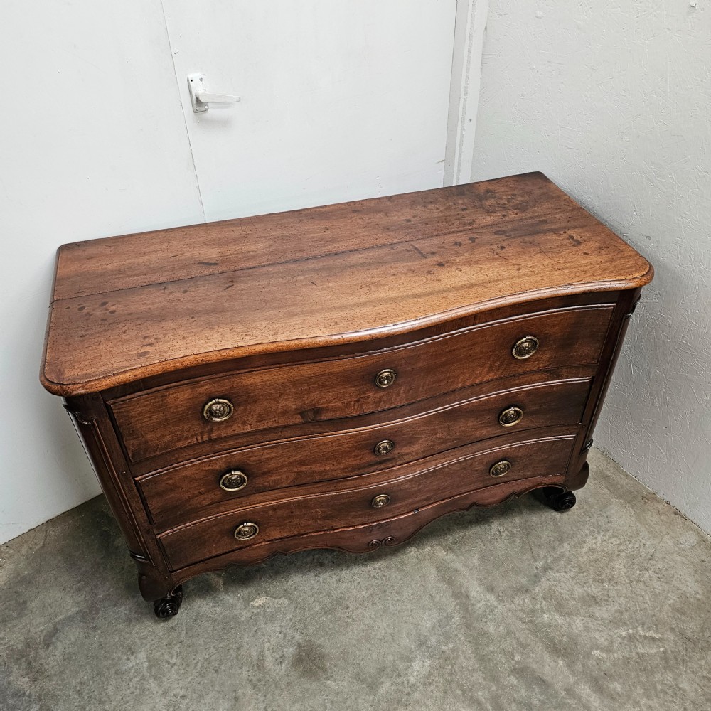 A nineteenth-century French serpentine wood commode featuring three drawers with brass ring handles and carved cabriole legs. View III