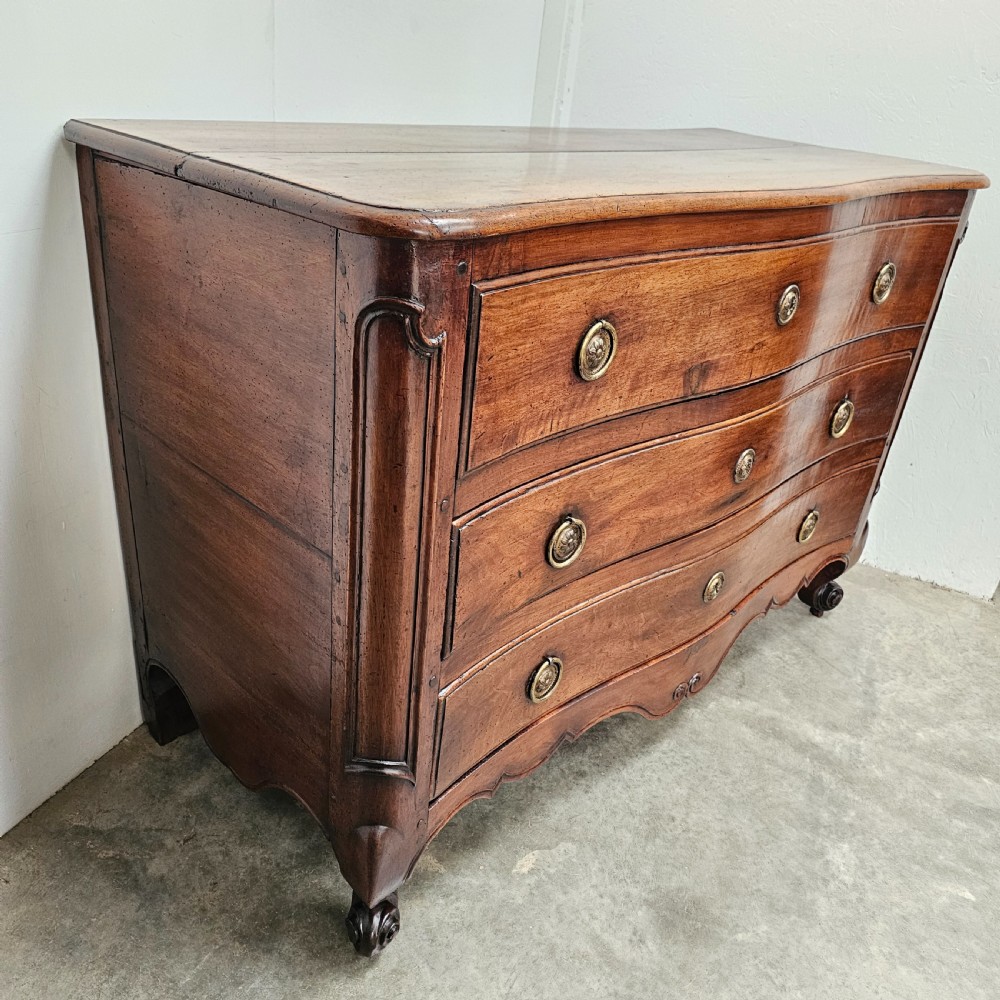 A nineteenth-century French serpentine wood commode featuring three drawers with brass ring handles and carved cabriole legs. View V