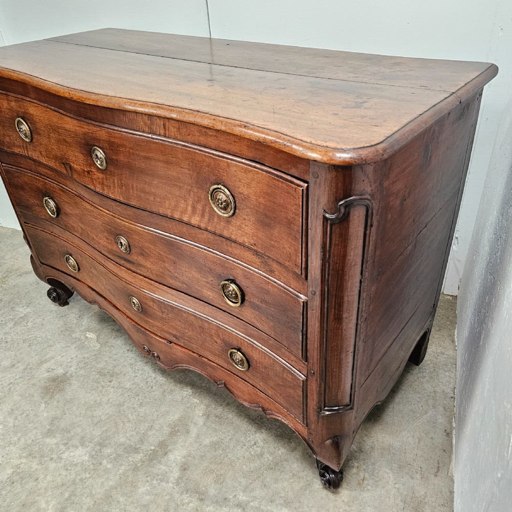 A nineteenth-century French serpentine wood commode featuring three drawers with brass ring handles and carved cabriole legs. View VI