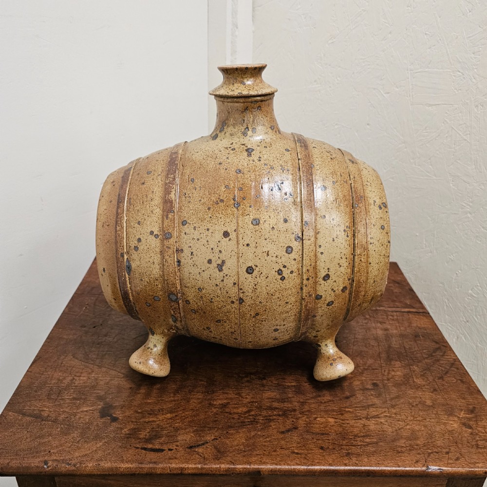 A horizontal ceramic barrel-shaped stoneware vinegar vessel with a speckled salt glaze finish, raised top opening, simulated wooden hoops, and integrated stoneware feet.