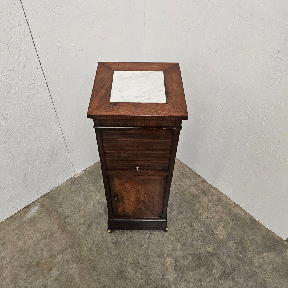 A tall, narrow 19th-century French mahogany nightstand featuring an inset marble top, a sliding tambour door section, and a lower single cupboard door. View II