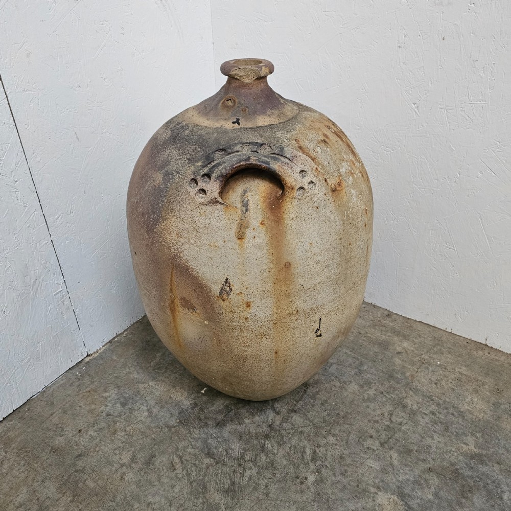 A large French earthenware walnut oil jar featuring a narrow rimmed mouth, dual shoulder lugs, and a textured earthy brown patina. View III