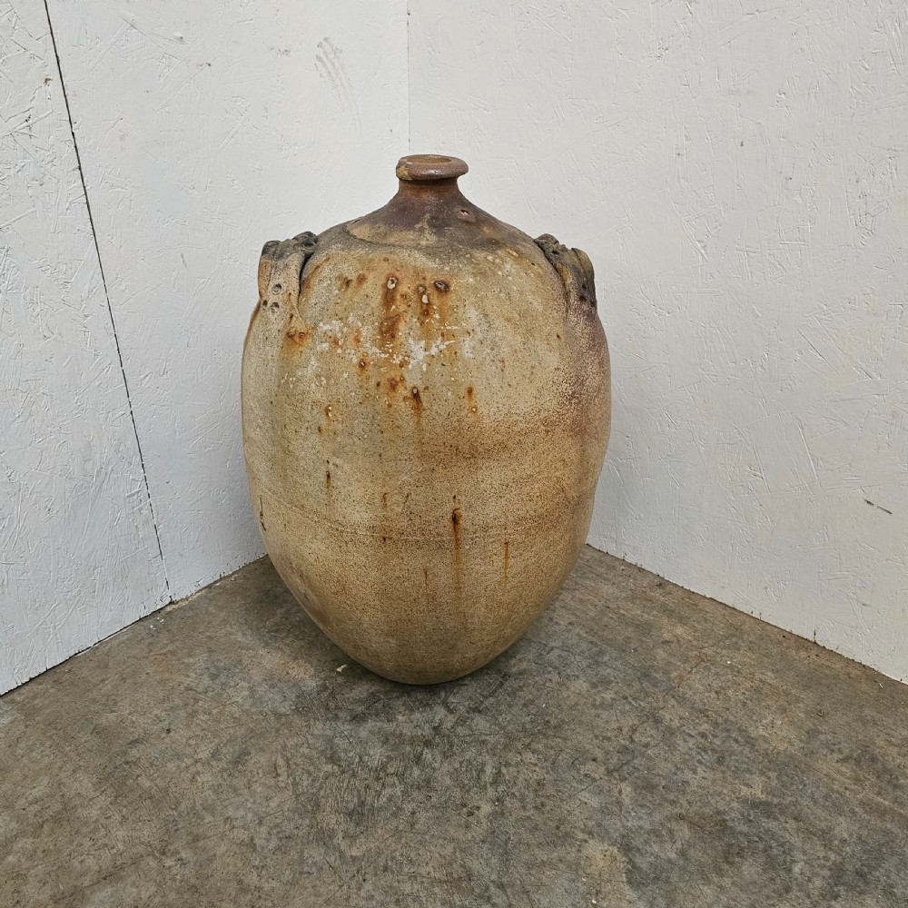 A large French earthenware walnut oil jar featuring a narrow rimmed mouth, dual shoulder lugs, and a textured earthy brown patina. View IV