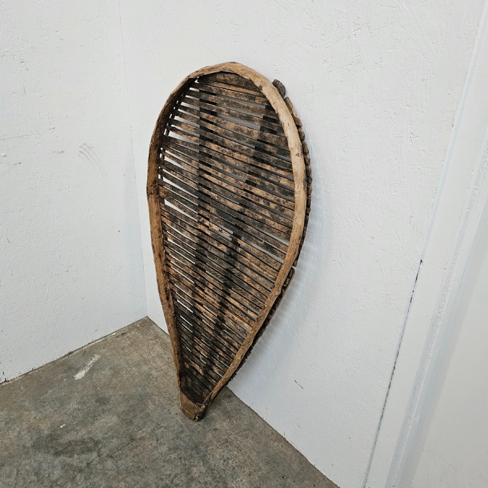 A teardrop-shaped French cleft hazel prune drying rack with horizontal wooden slats within a curved timber frame. View II