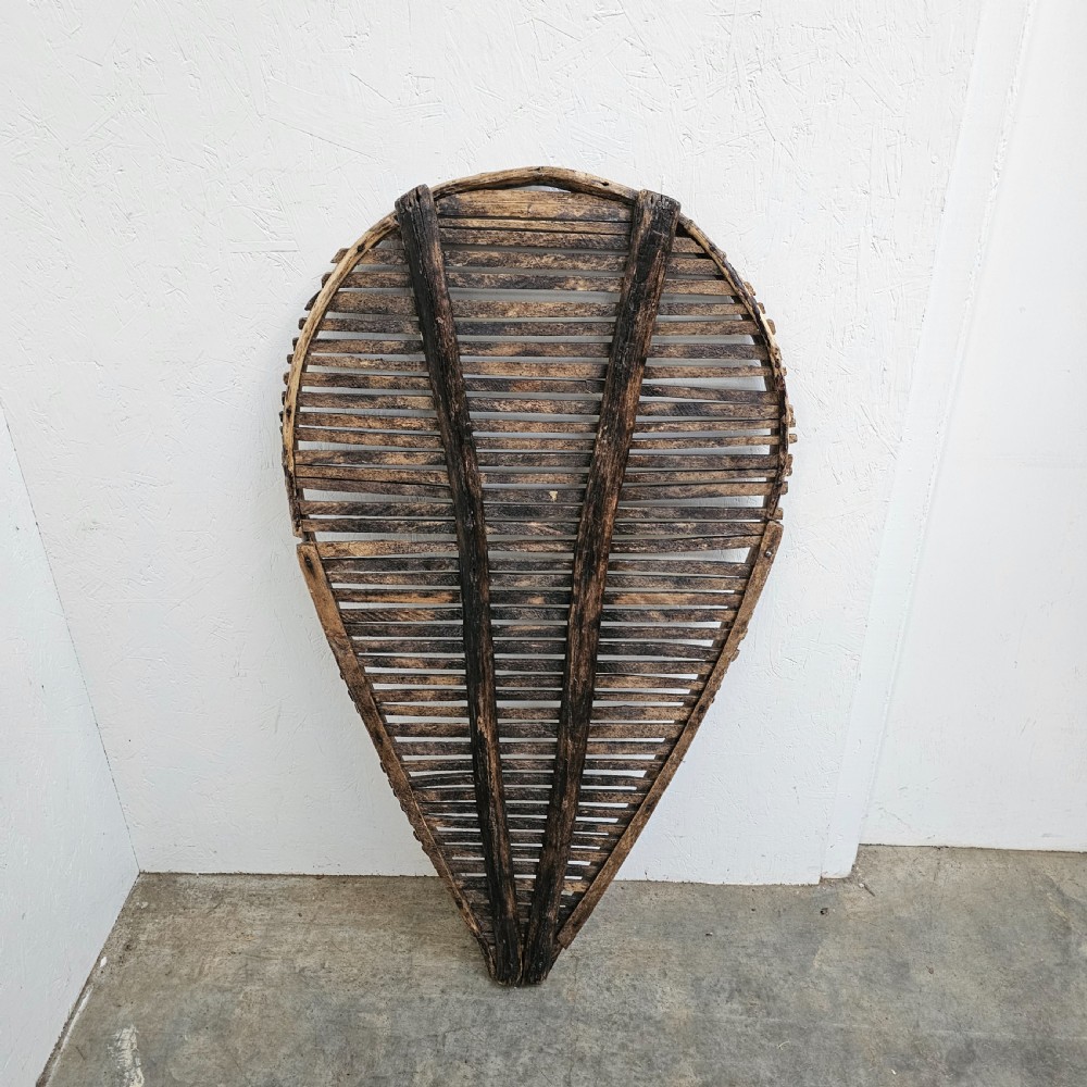 A teardrop-shaped French cleft hazel prune drying rack with horizontal wooden slats within a curved timber frame. View IV
