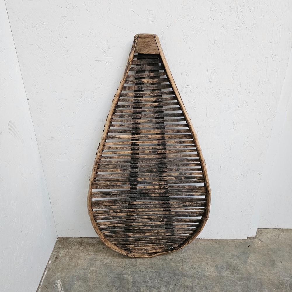 A teardrop-shaped French cleft hazel prune drying rack with horizontal wooden slats within a curved timber frame. View V
