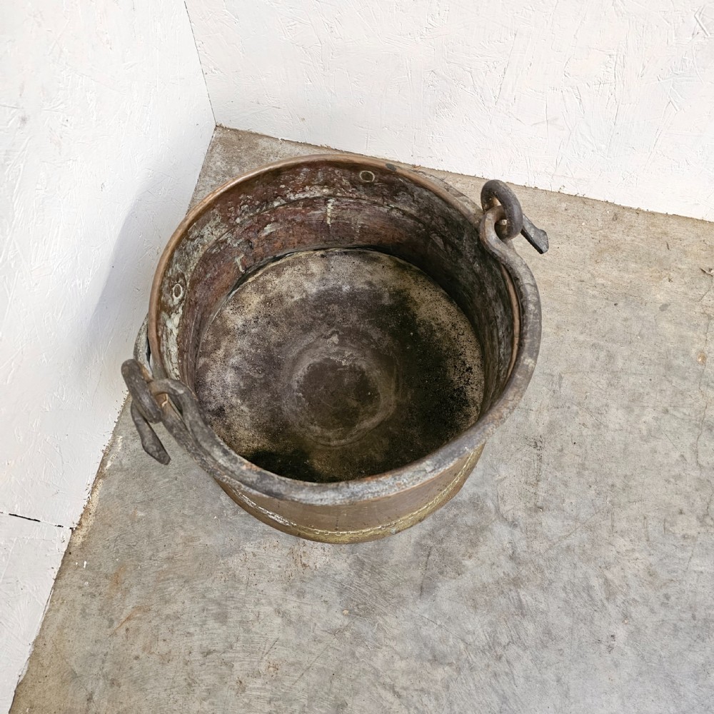 An antique French copper cauldron featuring a tapered body, rolled rim, and twin wrought-iron loop handles. View V