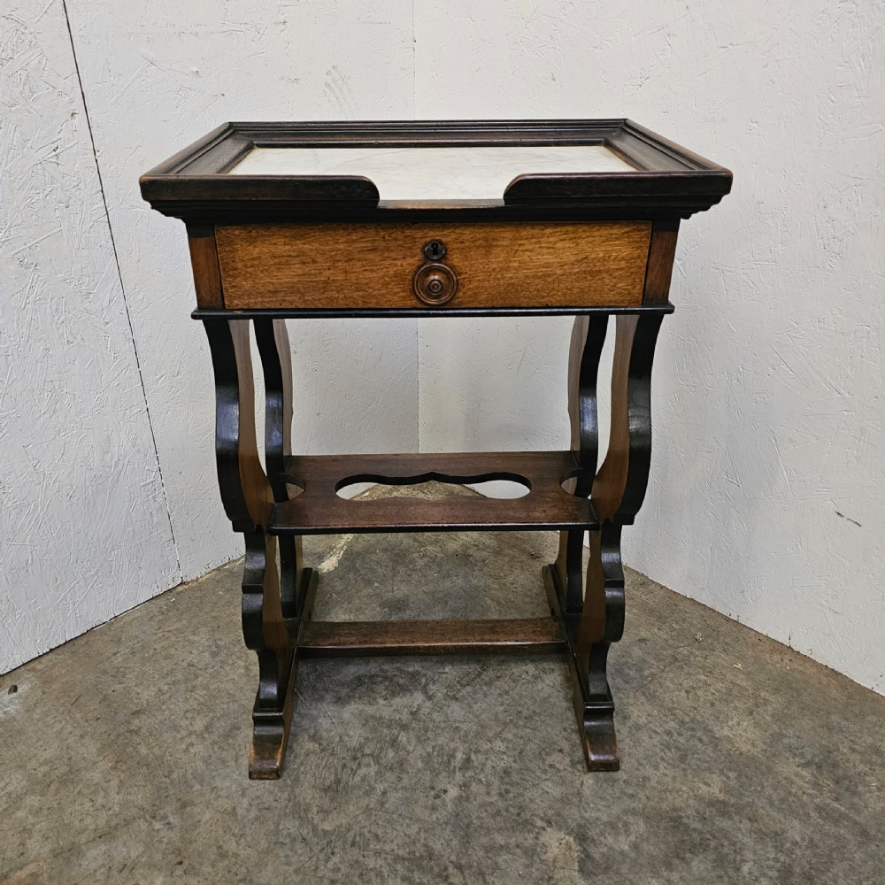 A French 19th-century walnut and ebonised stand featuring an inset marble top, a single frieze drawer, shaped supports, and a lower shelf.