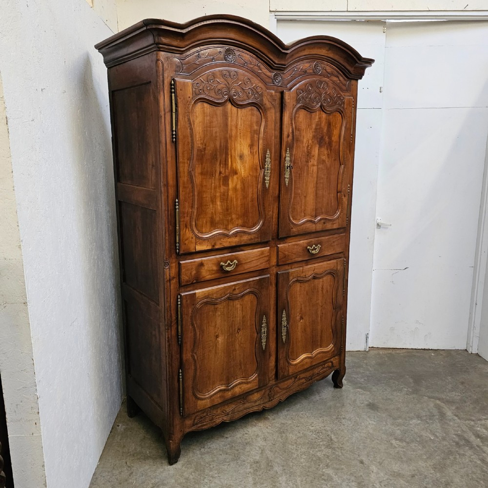 An 18th-century French carved walnut four-door armoire with shaped panels, central drawers, and decorative brass hardware. View II
