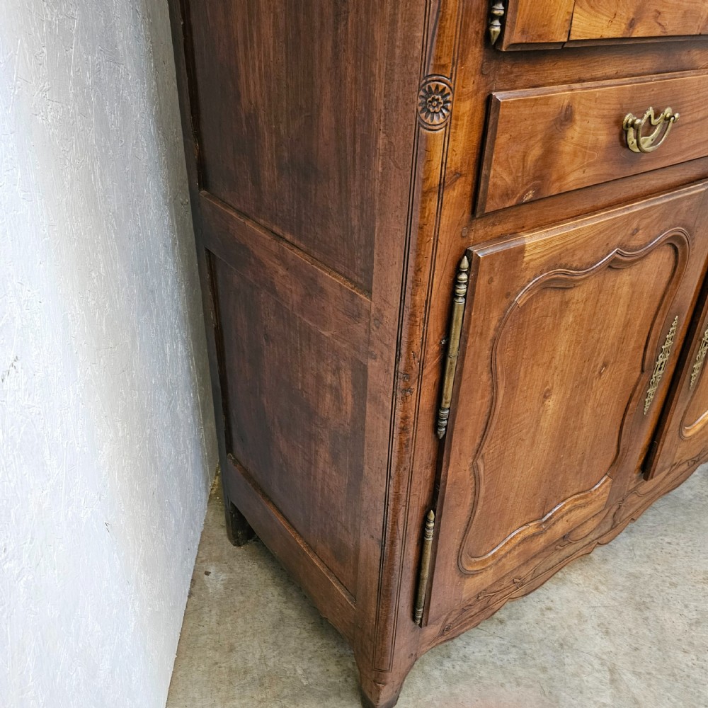 An 18th-century French carved walnut four-door armoire with shaped panels, central drawers, and decorative brass hardware. View III