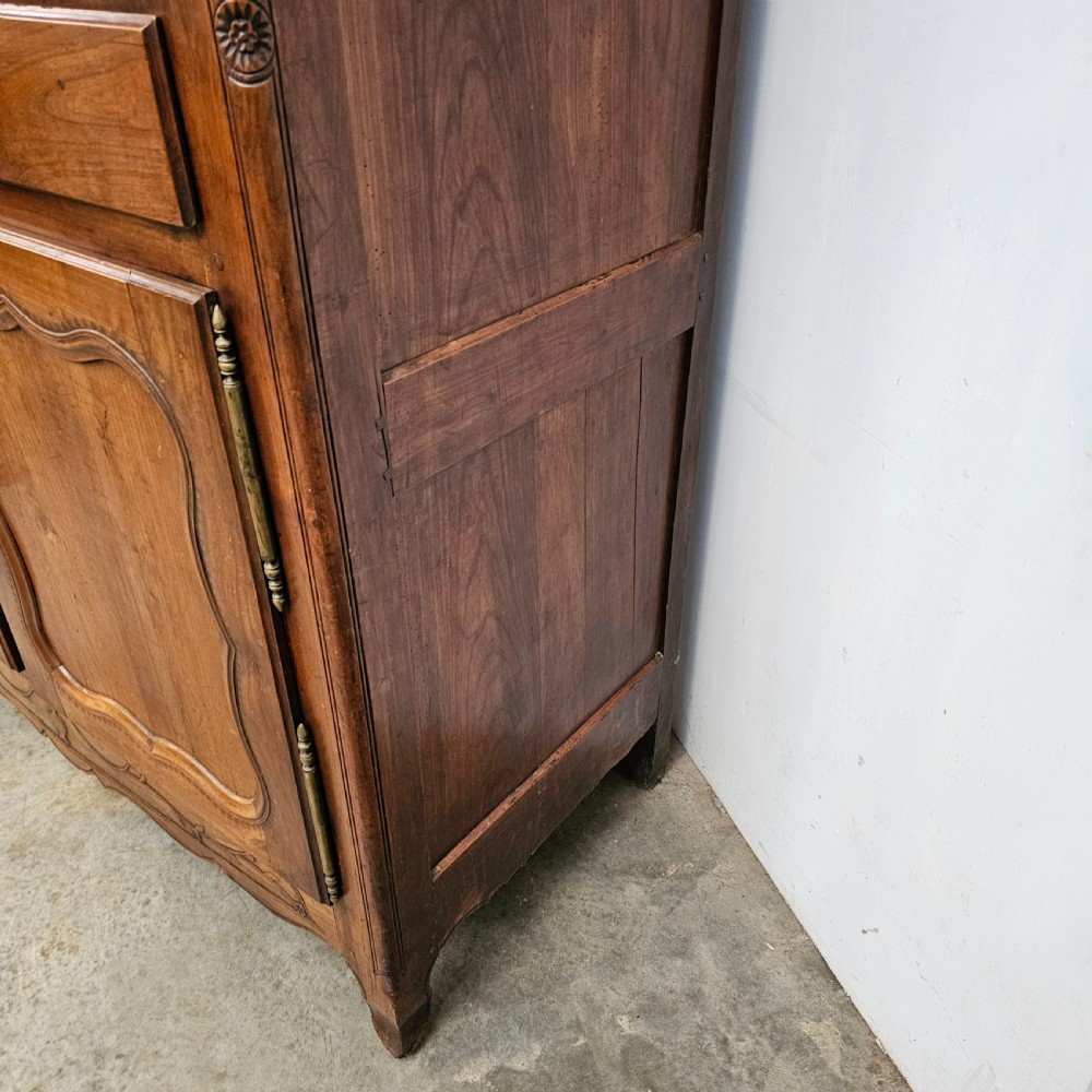 An 18th-century French carved walnut four-door armoire with shaped panels, central drawers, and decorative brass hardware. View VII