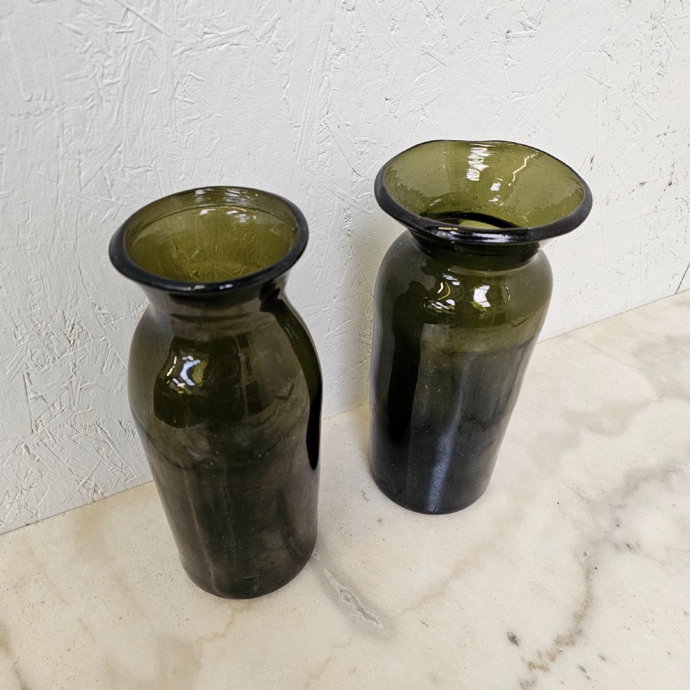 A pair of olive green hand-blown glass jars with cylindrical bases and wide flared rims. View II